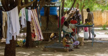 A man sits in front of a fruit stall under the shade of a tree at a camp for the internally displaced in al-Suwar, about 15 kilometers north of Wad Madani, Sudan, June 22, 2023. (AFP Photo)