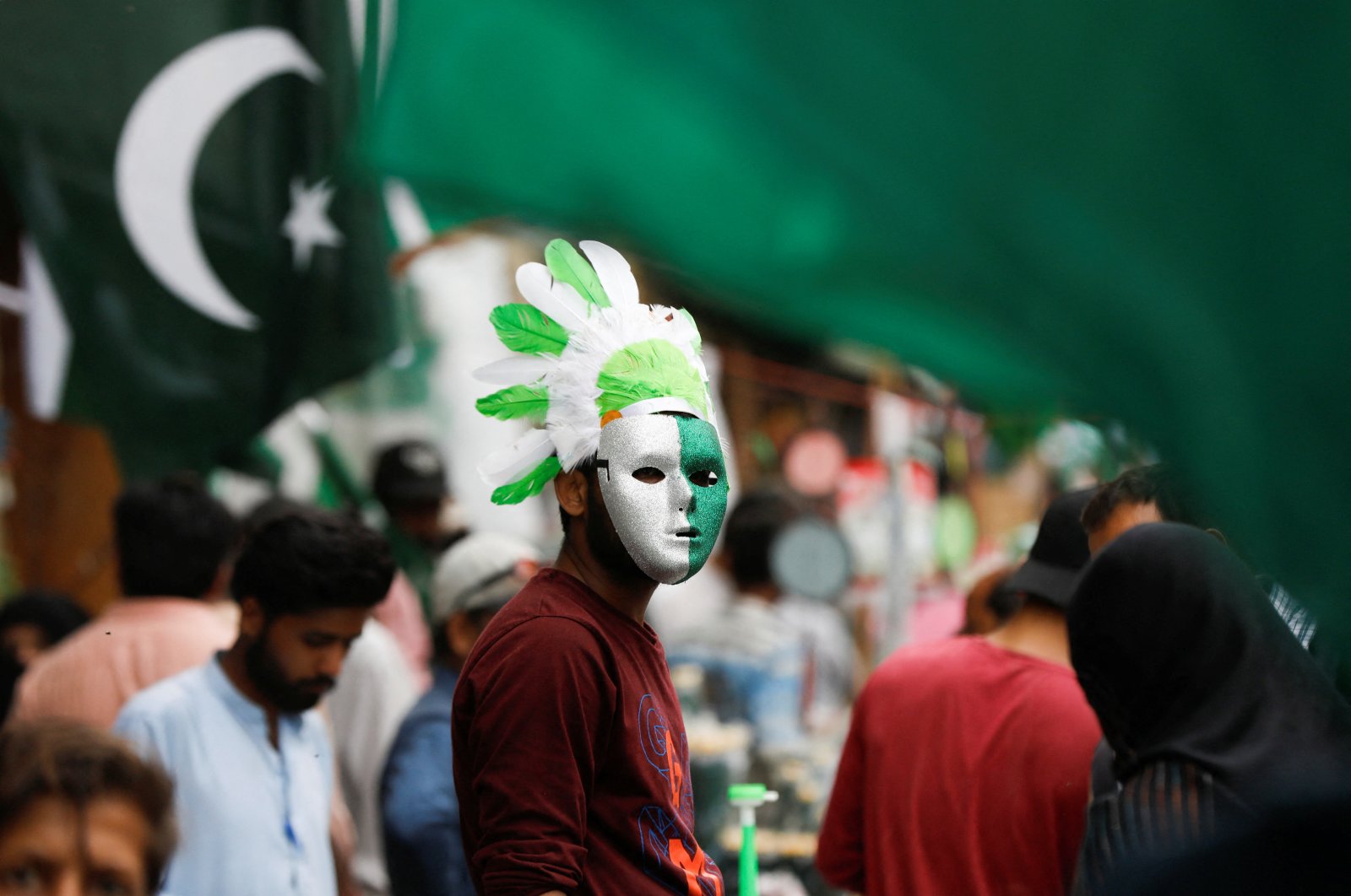 A vendor wears a mask and a headwear with the colours of the Pakistani flag, while selling national flags and patriotic memorabilia, ahead of Pakistan&#039;s Independence Day, along a market in Karachi, Pakistan, Aug. 2, 2023. (Reuters Photo)