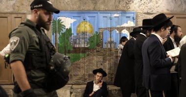 Israeli police officers guard as Orthodox Jews pray and read from the book of Eicha (Book of Lamentations) to mark Tisha B'av, near the door leading to the Al-Aqsa Mosque, in the Old City of Jerusalem, occupied Palestine, July 27, 2023. (EPA File Photo)