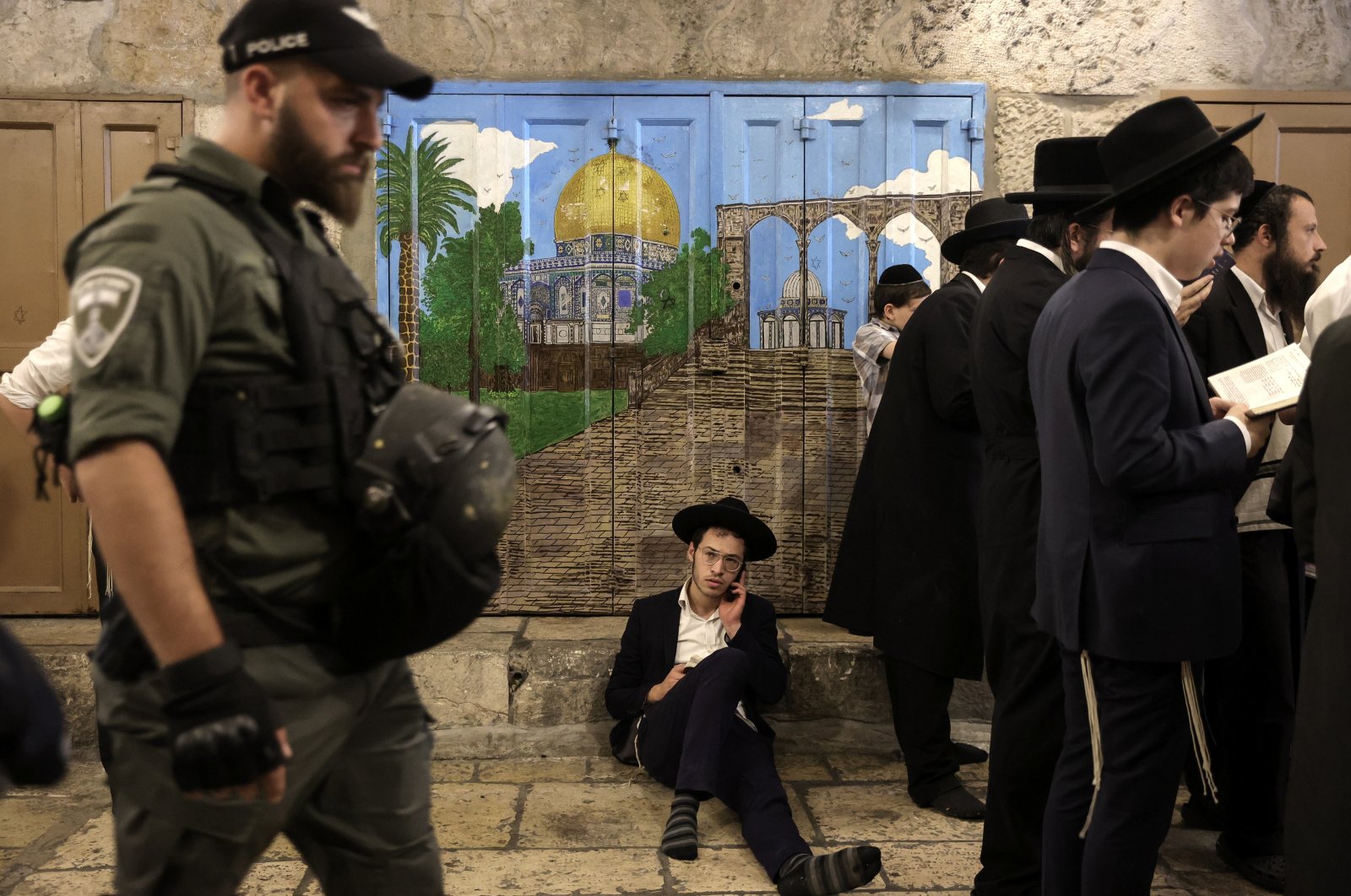 Israeli police officers guard as Orthodox Jews pray and read from the book of Eicha (Book of Lamentations) to mark Tisha B&#039;av, near the door leading to the Al-Aqsa Mosque, in the Old City of Jerusalem, occupied Palestine, July 27, 2023. (EPA File Photo)