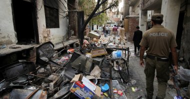 A police officer walks past the belongings of the residents along a street in a Christian neighborhood in Jaranwala, Pakistan, Aug. 17, 2023. (Reuters Photo)
