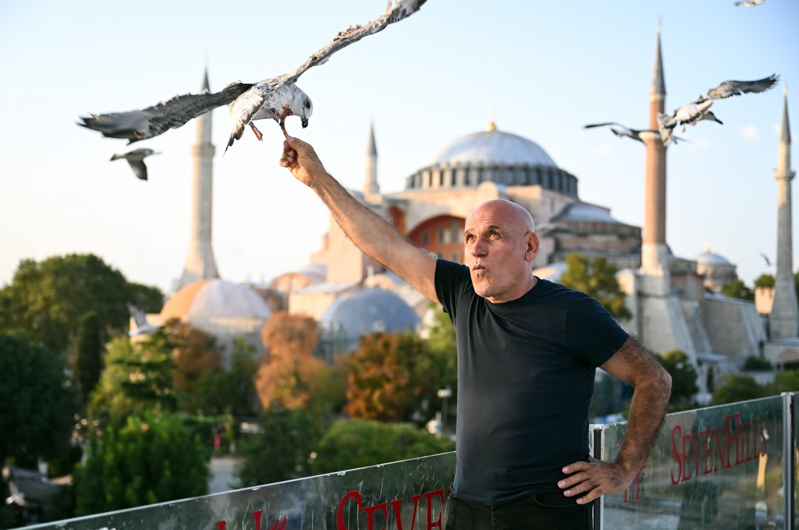 A tourist poses while feeding a seagull in front of the Hagia Sophia Grand Mosque, Istanbul, Türkiye, Aug. 21, 2023. (IHA Photo)
