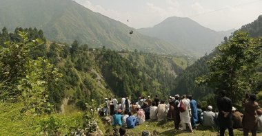 People watch as an army soldier slings down from a helicopter during a rescue mission to recover students stuck in a chairlift in Pashto village, Khyber Pakhtunkhwa province, Aug. 22, 2023. (AFP Photo)