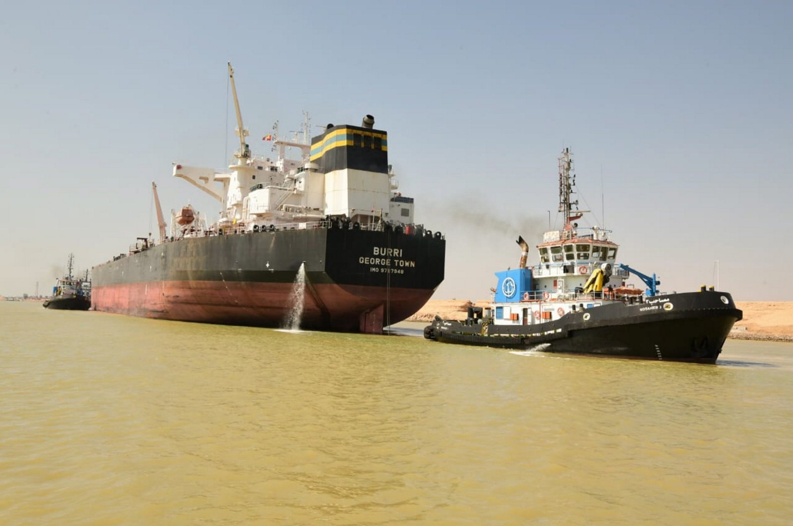 A tug boat pulls the Burri (L), an oil tanker flying the Cayman Island flag, after a collision with the Singapore-flagged BW Lesmes carrying LNG (not pictured), the Suez Canal, near the city of Suez, Egypt, Aug. 23, 2023. (Handout by the Suez Canal Authority via EPA Photo)