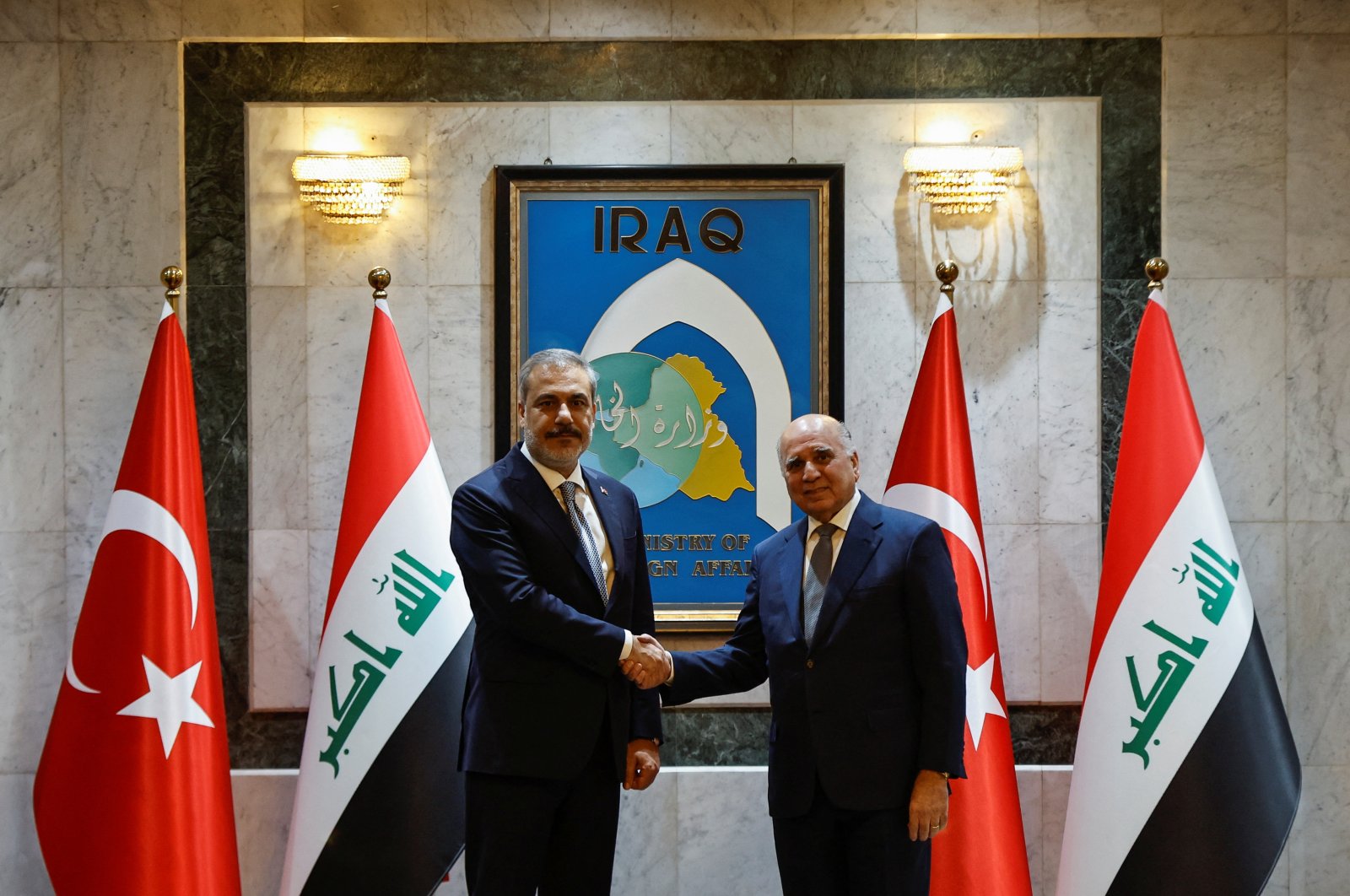 Foreign Minister Hakan Fidan (L) shakes hands with his Iraqi counterpart Fuad Hussein, Baghdad, Iraq, Aug. 22, 2023. (Reuters Photo)