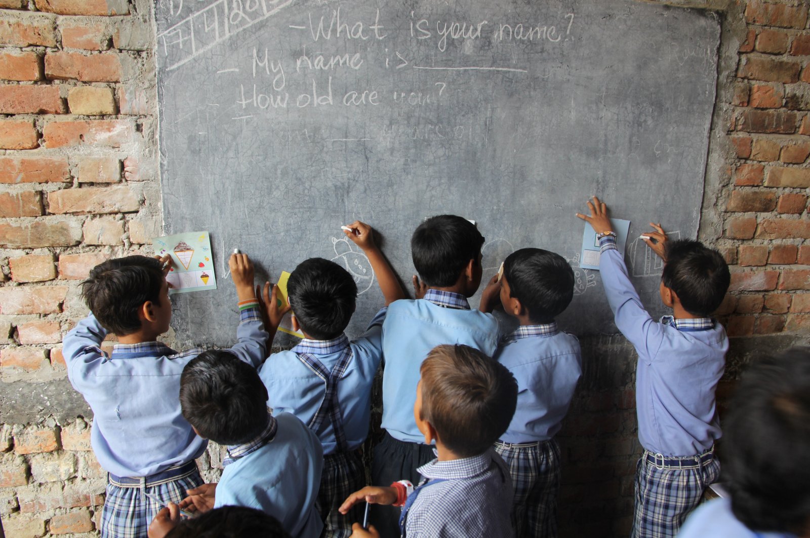 Children in rural indian village school learning to draw on the blackboard. (Shutterstock Photo)