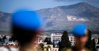 Members of the United Nations Peacekeeping Force in Cyprus (UNFICYP) from the British Household Cavalry Regiment visit the roof of the Ledra Palace in the U.N. buffer zone separating the divided capital of Nicosia; while the flag of the Turkish Republic of Northern Cyprus (TRNC) painted on the island's northern Kyrenia mountain range lies in the background, on April 5, 2023. (AFP Photo)
