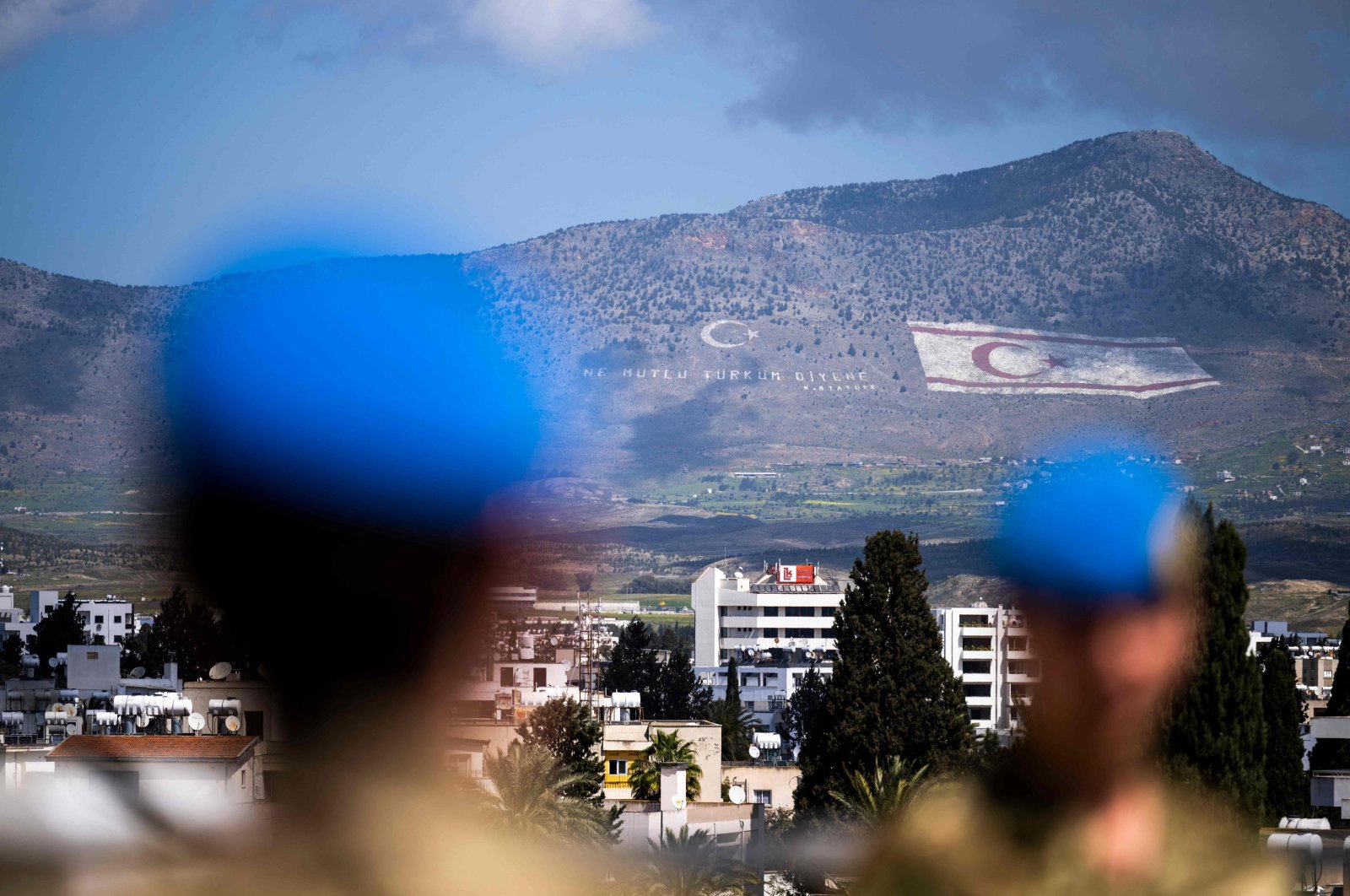 Members of the United Nations Peacekeeping Force in Cyprus (UNFICYP) from the British Household Cavalry Regiment visit the roof of the Ledra Palace in the U.N. buffer zone separating the divided capital of Nicosia; while the flag of the Turkish Republic of Northern Cyprus (TRNC) painted on the island&#039;s northern Kyrenia mountain range lies in the background, on April 5, 2023. (AFP Photo)