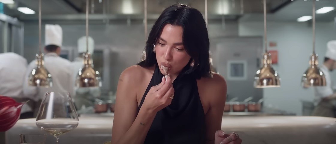A still shot of Dua Lipa eating pigeon leg in a Vogue video.