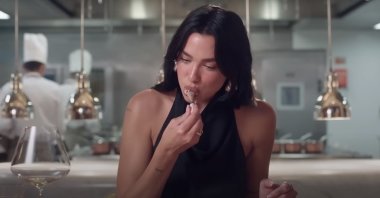 A still shot of Dua Lipa eating pigeon leg in a Vogue video.