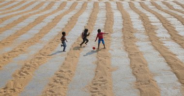 Children play with a ball after rice is spread for drying at a rice mill on the outskirts of Kolkata, India, Jan. 31, 2019. (Reuters Photo)