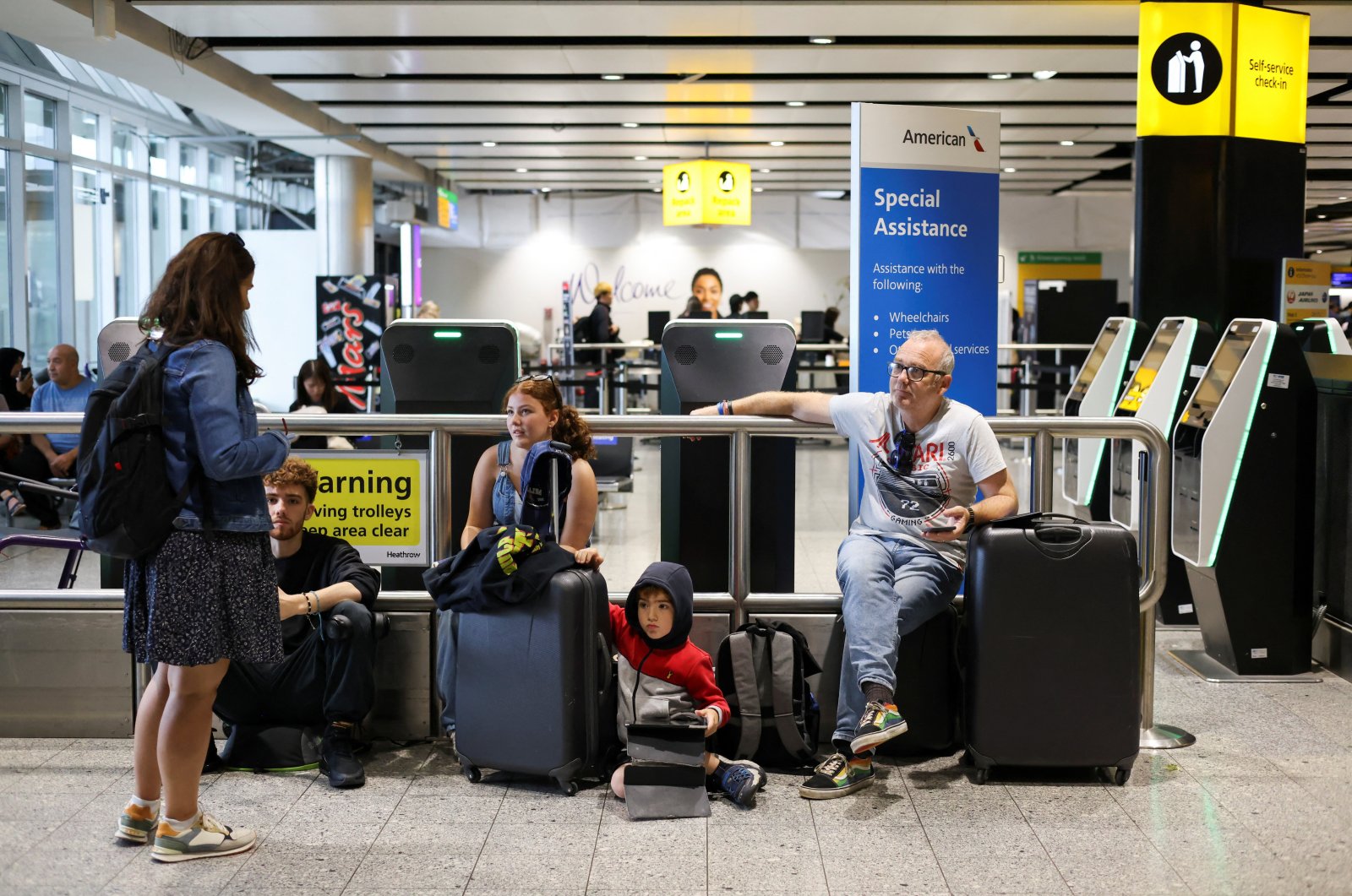 A family waits as their flight delays as Britain&#039;s National Air Traffic Service (NATS) restricts U.K. air traffic due to a technical issue causing delays, in London, United Kingdom, Aug. 28, 2023. (Reuters Photo)