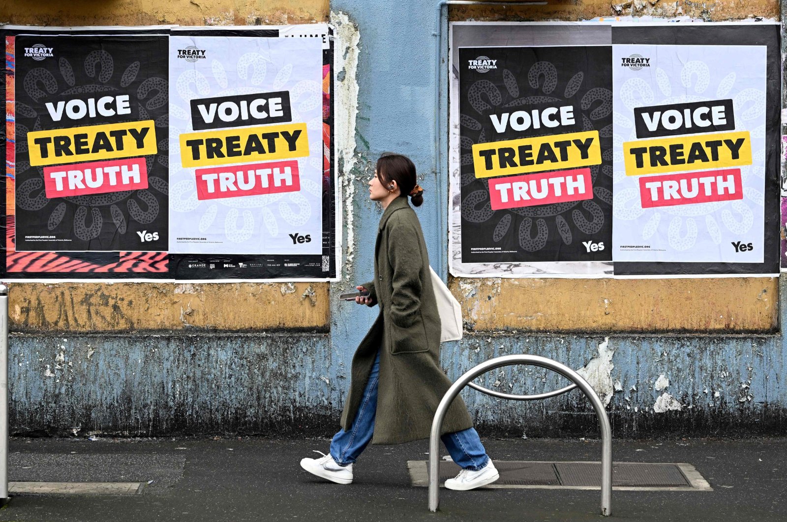 A woman walks past posters advocating for an Aboriginal voice and treaty ahead of an upcoming referendum, Melbourne, Australia, Aug. 30, 2023. (AFP Photo)