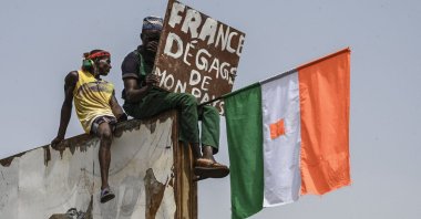 A man holds a placard and a Niger national flag as they protest outside the Niger and French airbase, Niamey, Niger, Sept. 2, 2023. (AFP Photo)