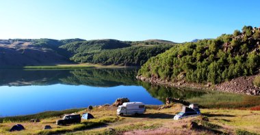 Camping cars and tents in front of a scenic mirroring crater lake near Lake Van in eastern Türkiye. (Shutterstock Photo)