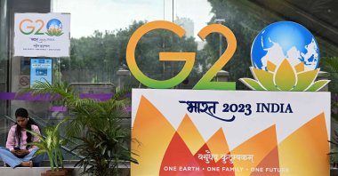 A woman sits near a G-20 summit logo installed along a street in New Delhi, India, Sept. 6, 2023. (AFP Photo)
