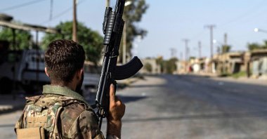 A PKK/YPG terrorist stands guard along a road as others deploy to impose a curfew in the town of al-Busayrah in the Deir el-Zour province, northeastern Syria, Sept. 4, 2023. (AFP Photo)