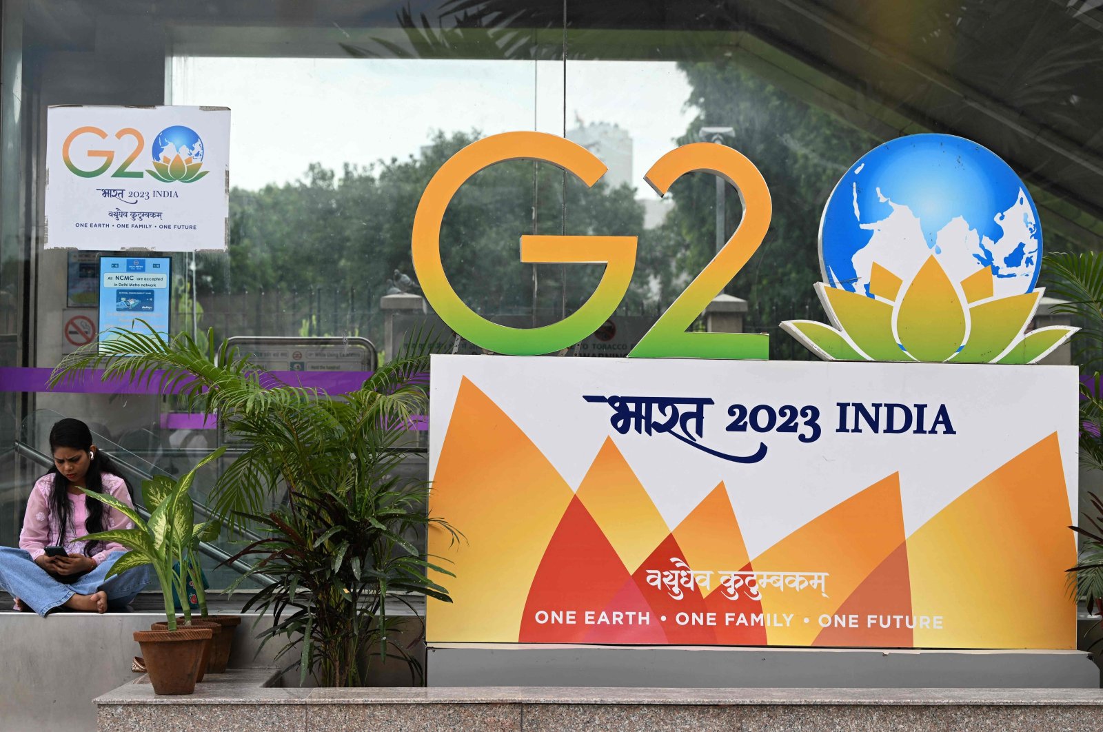 A woman sits near a G-20 summit logo installed along a street in New Delhi, India, Sept. 6, 2023. (AFP Photo)