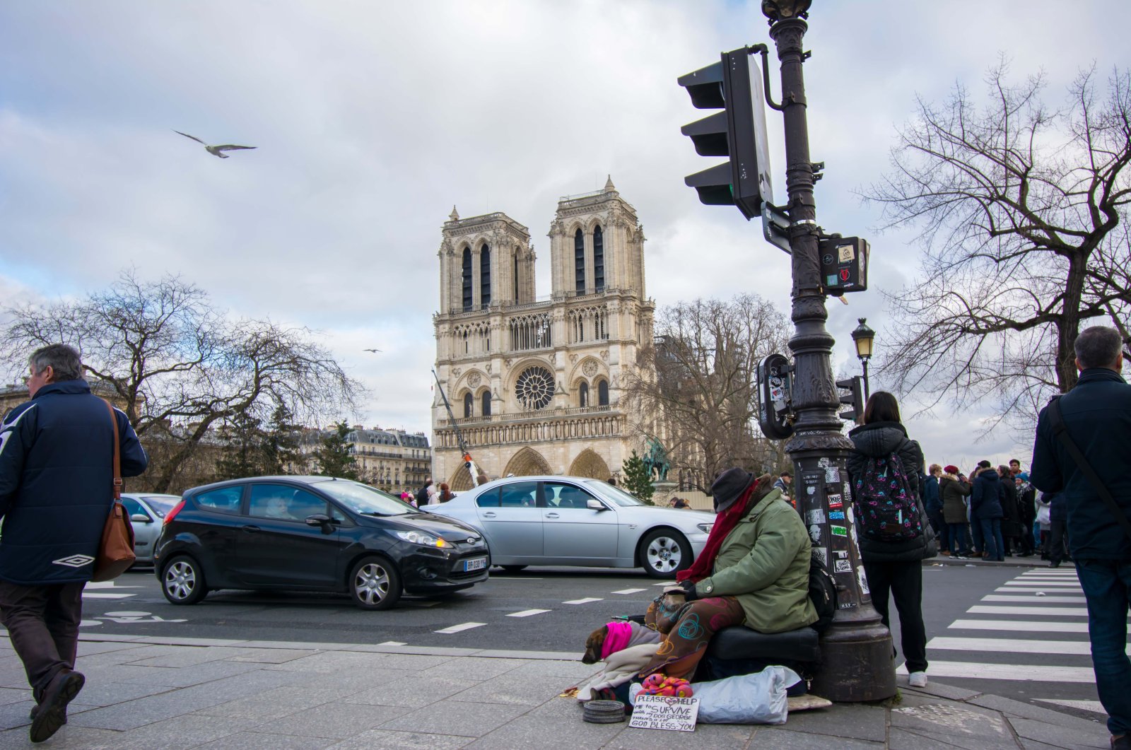 Homeless man with his dog asking for money in front of Notre Dame Cathedral in Paris, France, Dec. 2, 2020. (Shutterstock File Photo)