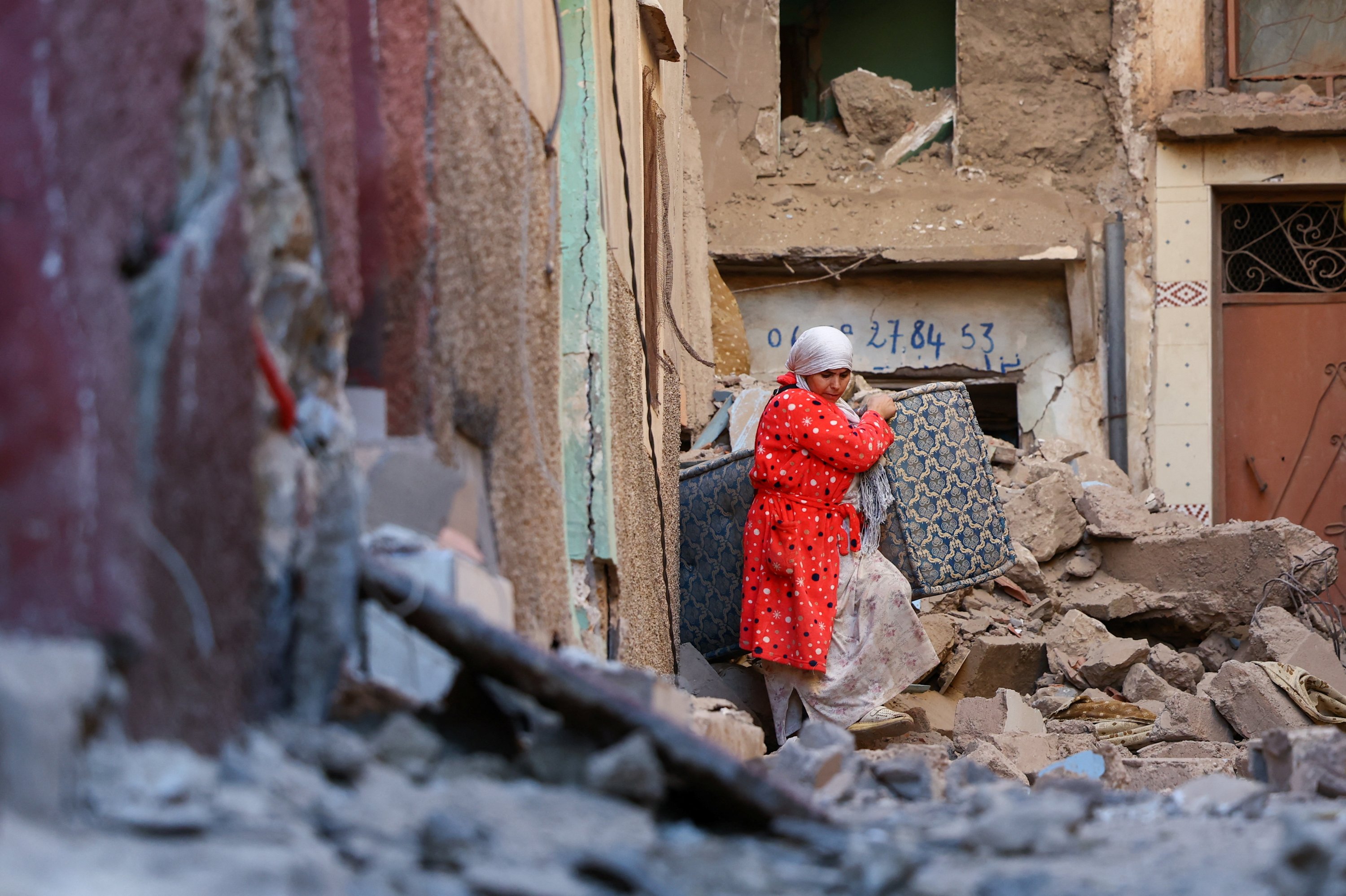 A woman carries belongings out of a damaged building, in the aftermath of a deadly earthquake in Moulay Brahim, Morocco, Sept. 10, 2023. (Reuters Photo)