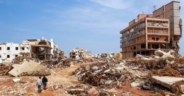 Men walk past debris of buildings caused by flash floods in Derna, eastern Libya, Sept. 12, 2023. (AFP Photo)
