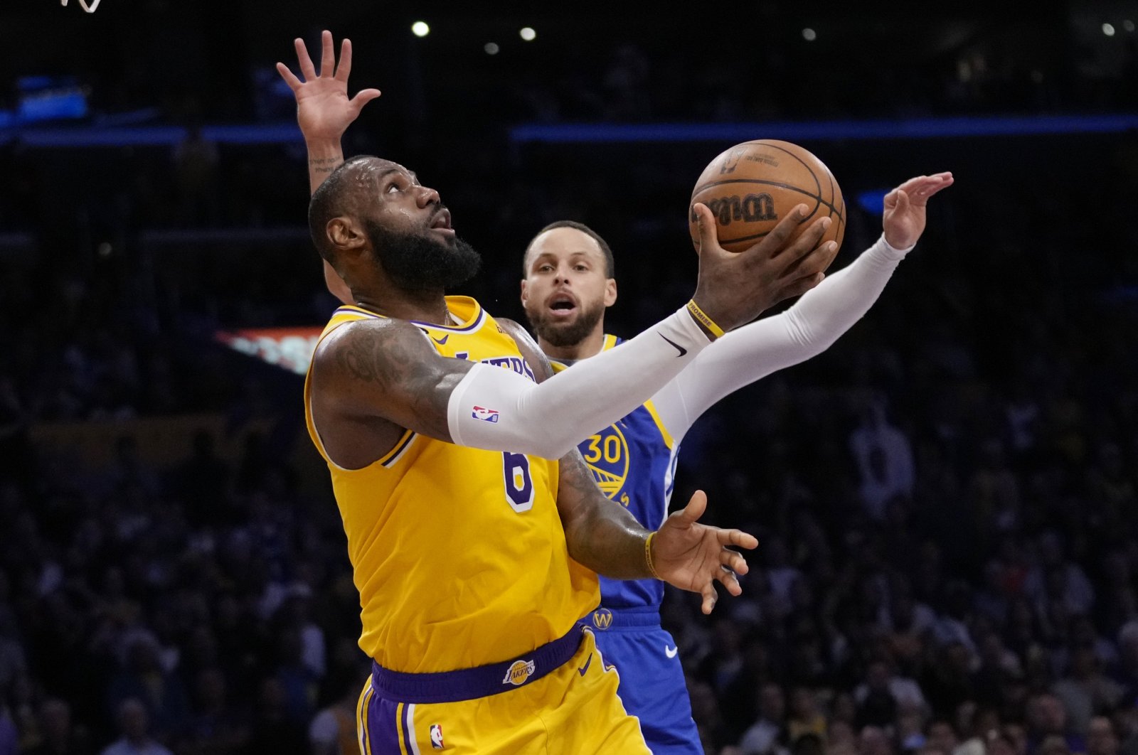 Lakers forward LeBron James scores past Golden State Warriors guard Stephen Curry in an NBA basketball Western Conference semifinal series Friday, May 12, 2023, in Los Angeles. (AP Photo/Ashley Landis)