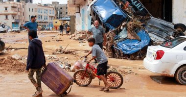 A boy pulls a suitcase past debris in a flash-flood damaged area in Derna, eastern Libya, on Sept. 11, 2023. (AFP Photo)