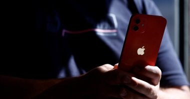A man poses with an Apple iPhone 12 in a mobile phone store in Nantes, France, Sept. 13, 2023. (Reuters Photo)
