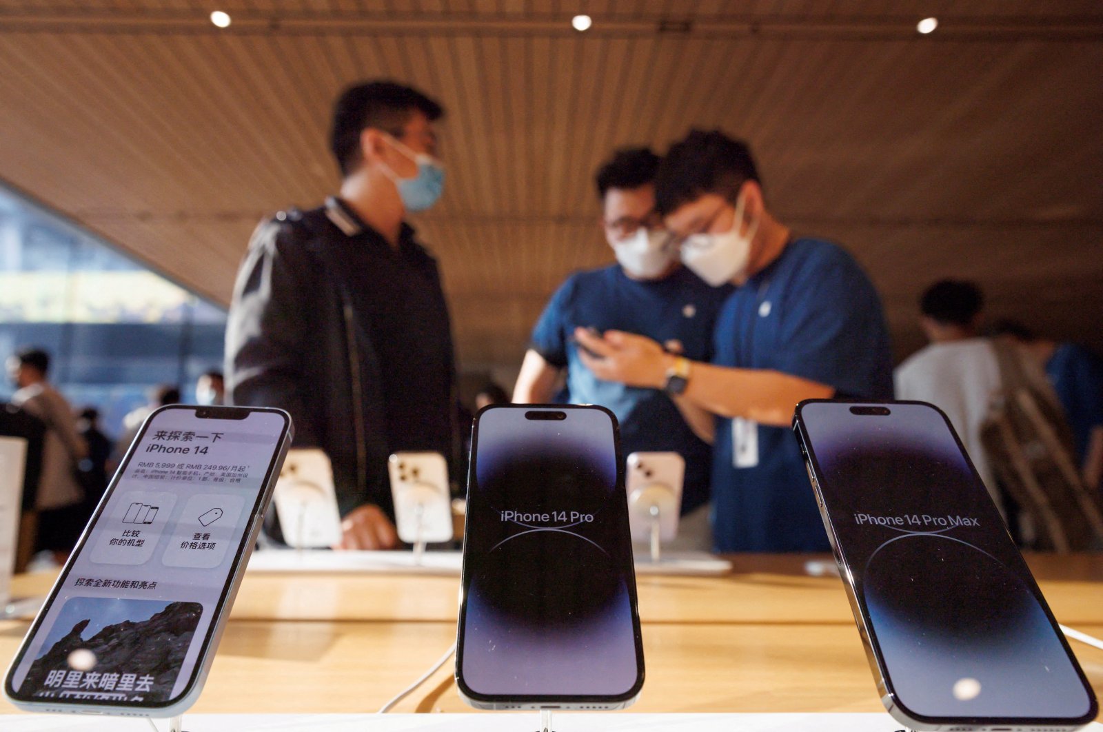 A customer talks to sales assistants in an Apple store as Apple Inc&#039;s new iPhone 14 models go on sale in Beijing, China, Sept. 16, 2022. (Reuters Photo)