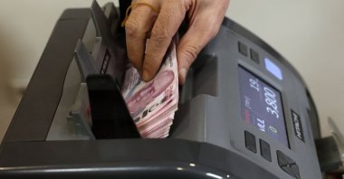 A teller uses a machine to count Turkish lira banknotes at a foreign exchange office in Ankara, Türkiye, July 20, 2023. (AFP Photo)