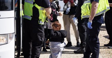 A child rescued from a boat crossing the English Channel is taken to a Home Office bus in Kent, U.K., Aug. 21, 2023. (EPA Photo)