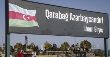 People walk next to a poster "Karabakh is Azerbaijan! Ilham Aliev" at the Military Trophy Park, containing war trophies seized by the Armed Forces of Azerbaijan during the 2020 Karabakh conflict, Baku, Azerbaijan, Sept. 5, 2023. (EPA Photo)