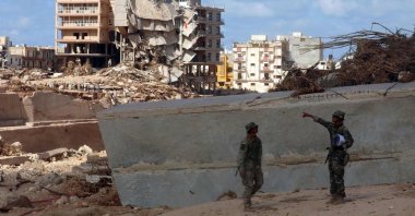 Soldiers stand in front of buildings destroyed in flash floods after the Mediterranean storm "Daniel" hit Libya's eastern city of Derna, on Sept. 14, 2023. (AFP Photo)