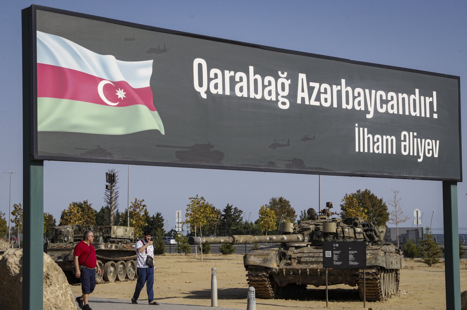 People walk next to a poster "Karabakh is Azerbaijan! Ilham Aliev" at the Military Trophy Park, containing war trophies seized by the Armed Forces of Azerbaijan during the 2020 Karabakh conflict, Baku, Azerbaijan, Sept. 5, 2023. (EPA Photo)