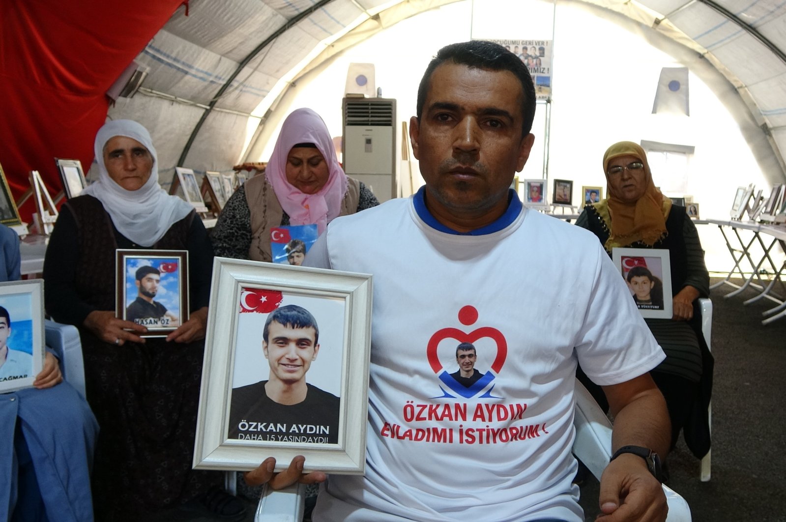 Süleyman Aydın holds the picture of his son Özkan who was 15 years old when he was kidnapped by the PKK, Diyarbakır, southeastern Türkiye, Aug. 26, 2023. (İHA Photo)