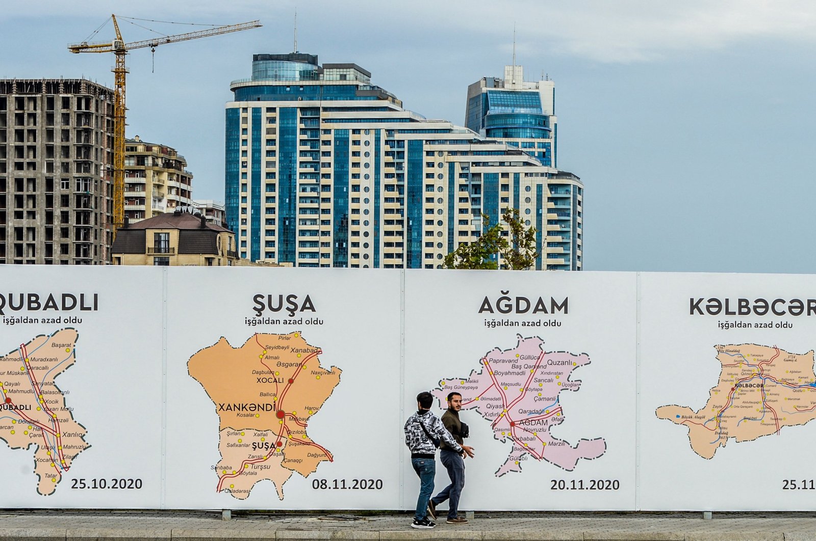 People walk past a poster showing the maps of the towns of Karabakh, Baku, Azerbaijan, Sept. 13, 2023. (AFP Photo)