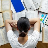 A tired university student rests while doing homework at her desk in this undated file photo. (Getty Image File Photo)