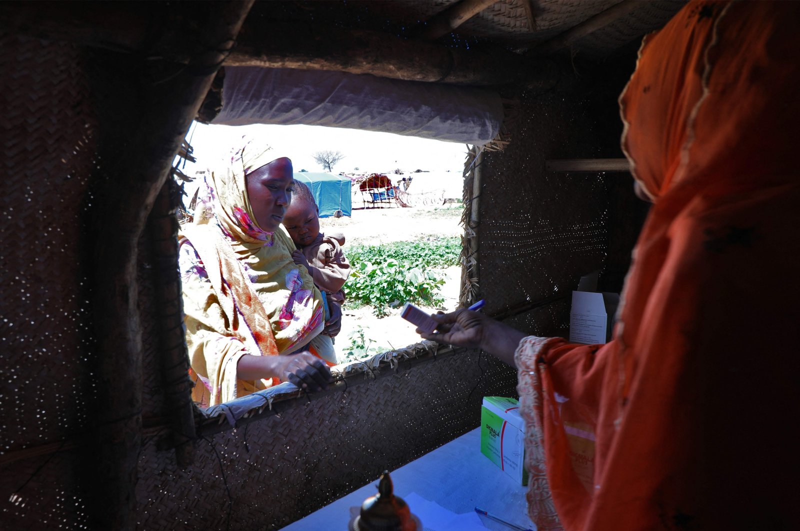 A woman who fled the war in Sudan collects medicine from a makeshift pharmacy at a refugee camp near Adre, Chad, Aug. 14, 2023. (AFP Photo)