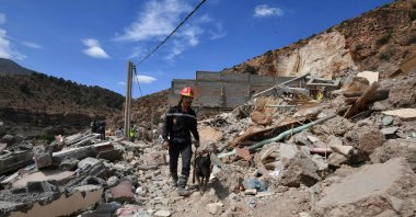 A firefighter walks with a dog amid ongoing search operations in the village of Imi N'Tala following the powerful 6.8-magnitude earthquake, Morocco, Sept. 17, 2023. (AFP Photo)