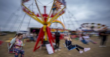 Children enjoy a swing ride at a fair in Hagioaica, Romania, Sept. 16, 2023. (AP Photo)