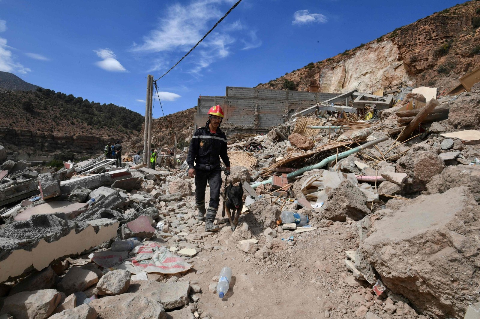 A firefighter walks with a dog amid ongoing search operations in the village of Imi N&#039;Tala following the powerful 6.8-magnitude earthquake, Morocco, Sept. 17, 2023. (AFP Photo)