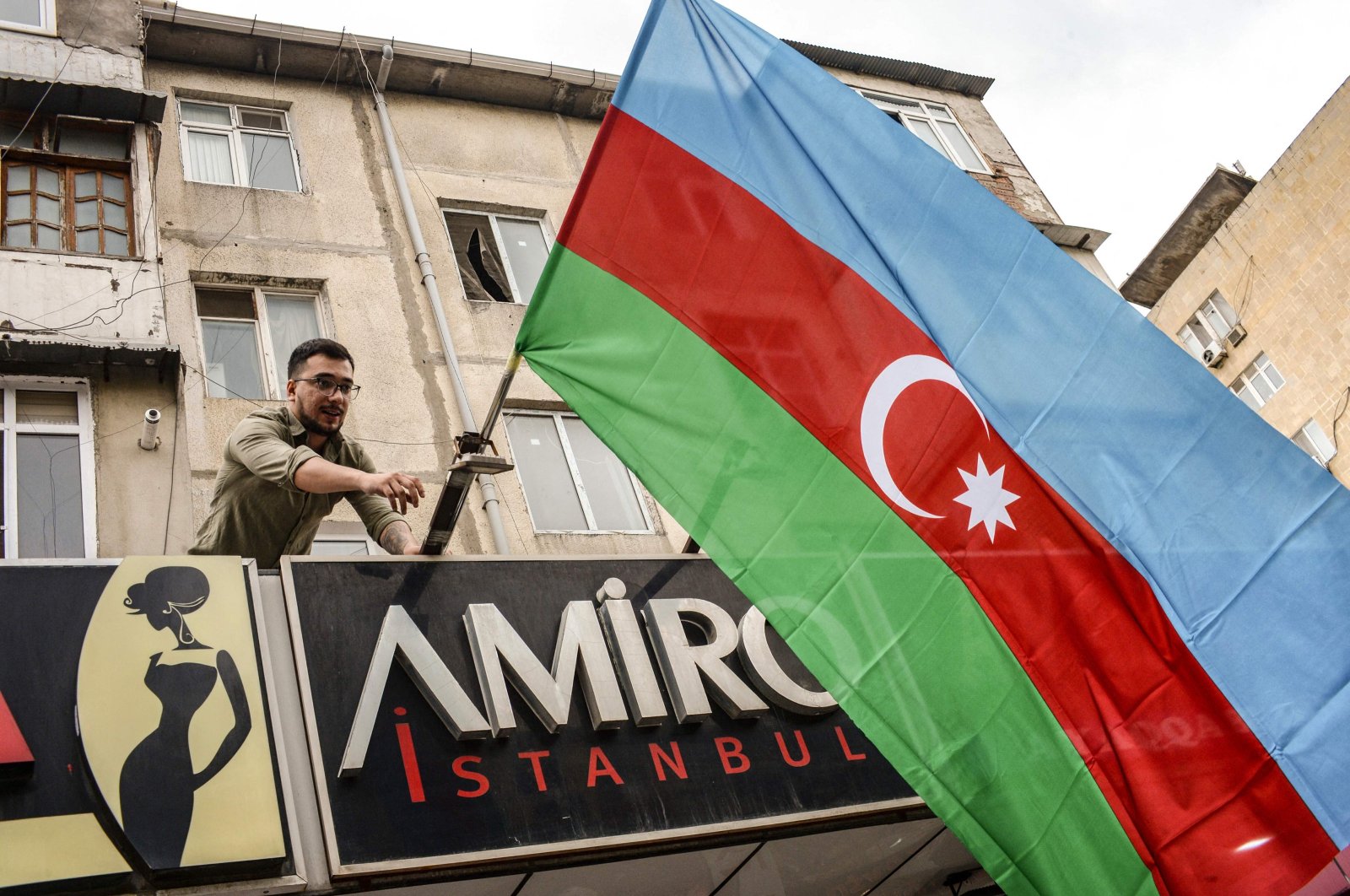 An Azerbaijani resident hangs a state flag in support of the country&#039;s offensive in the Karabakh region, in Baku, Azerbaijan on September 20, 2023. (AFP Photo)