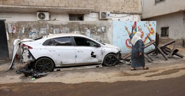 A woman walks past a damaged car following an Israeli military raid at Jenin refugee camp, occupied West Bank, Sept. 20, 2023. (EPA Photo)