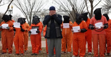 Activists in orange jumpsuits, representing the 35 men who are still being held at the U.S. detention facility in Guantanamo Bay, Cuba, say a prayer as they participate in a protest in front of the White House, Washington, U.S., Jan. 11, 2023. (Getty Images Photo)