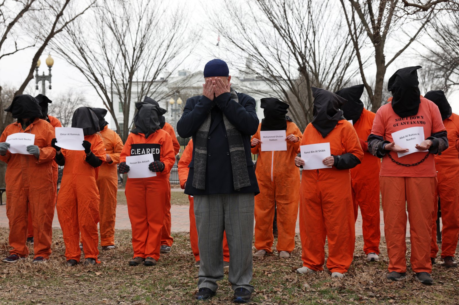 Activists in orange jumpsuits, representing the 35 men who are still being held at the U.S. detention facility in Guantanamo Bay, Cuba, say a prayer as they participate in a protest in front of the White House, Washington, U.S., Jan. 11, 2023. (Getty Images Photo)