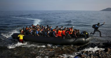 An Afghan migrant jumps off an overcrowded raft onto a beach on the Greek island of Lesbos Oct.19, 2015. (Reuters File Photo)