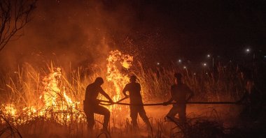 Police officers use a hose in effort to extinguish wildfires in Ogan Ilir regency, South Sumatra province, Indonesia, Sept. 20, 2023. (Reuters Photo)