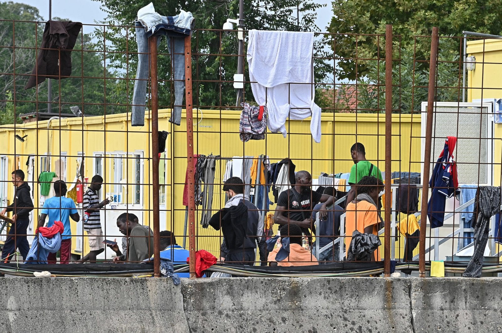 Migrants dry their clothes on a fence at the Red Cross reception center in Via Tres, Turin, Italy, Sept. 20, 2023. (EPA Photo)
