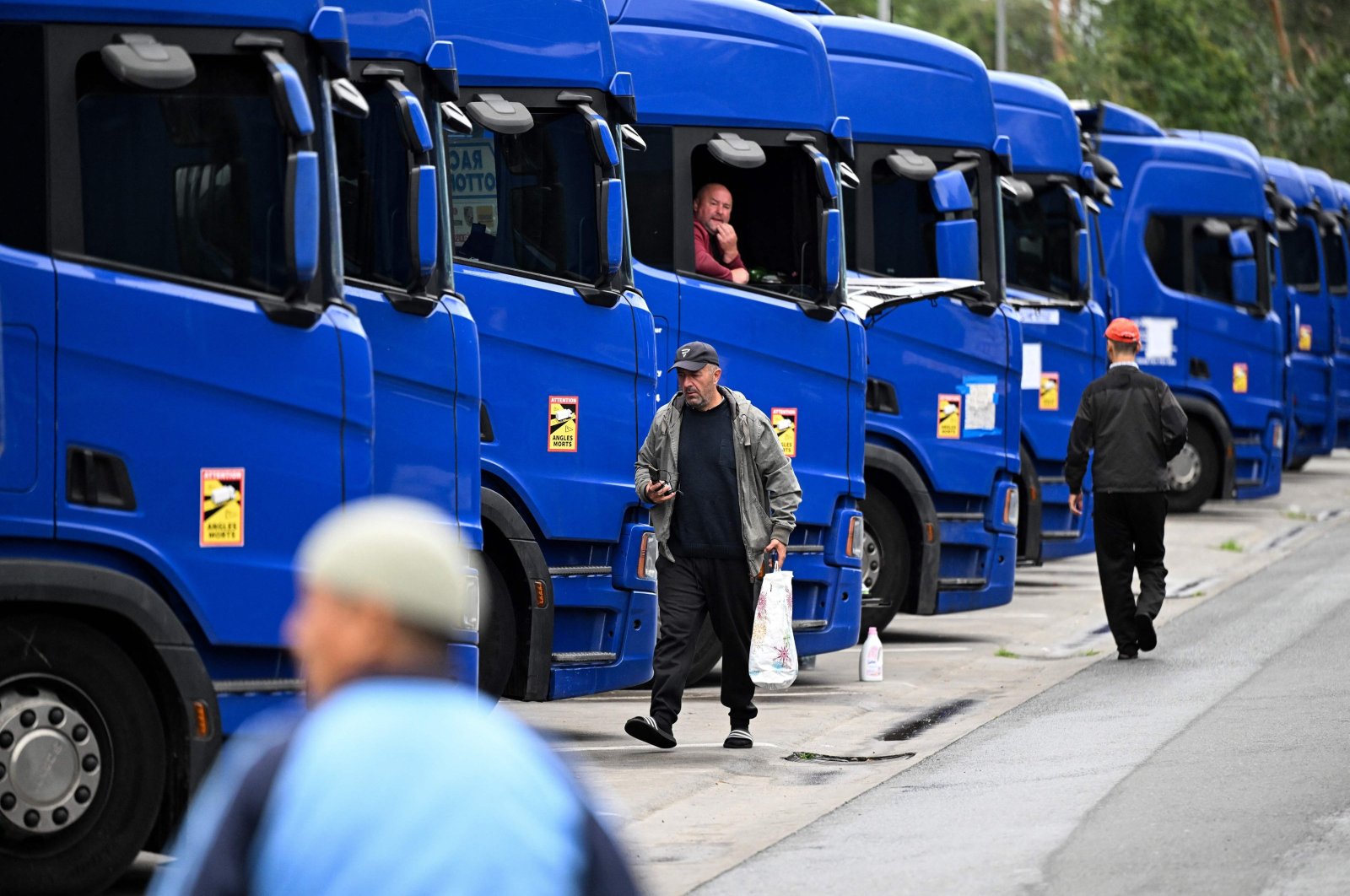 Truck drivers walk past parked trucks outside Frankfurt am Main, western Germany, Sept. 22, 2023. (AFP Photo)