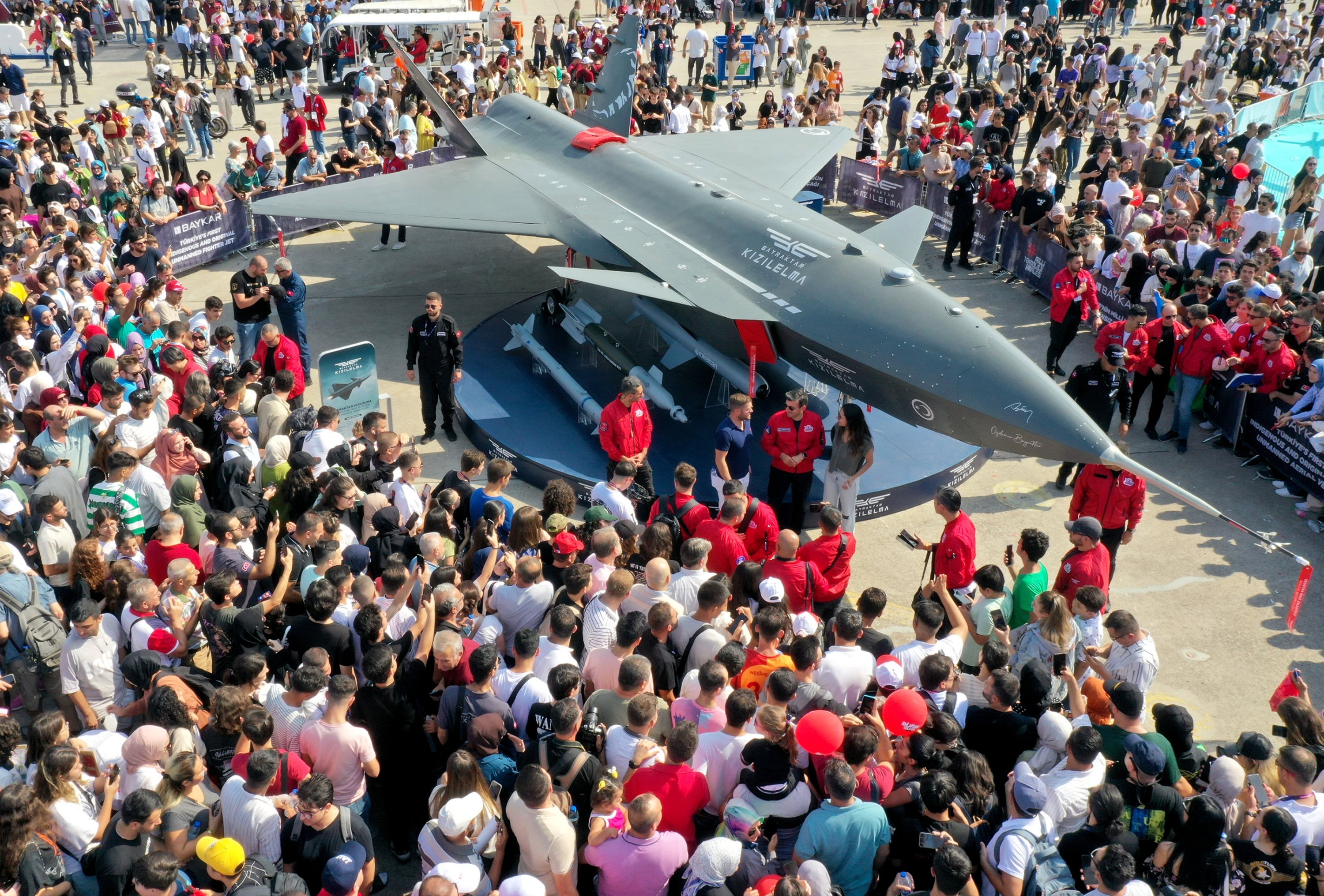 Selçuk Bayraktar, the chairperson of the T3 board of trustees and the chairperson of Teknofest's board of directors, poses for a photo with visitors in front of the famed Kızılelma fighter jet, Izmir, western Türkiye, Sept. 27, 2023. (AA Photo)